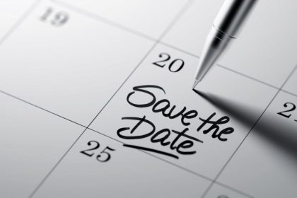 Closeup of a personal agenda setting an important date written with pen. The words Save the date written on a white notebook to remind you an important appointment.